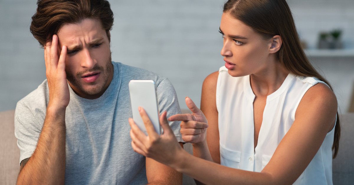 Woman showing a man his cellphone looking angry and accusing